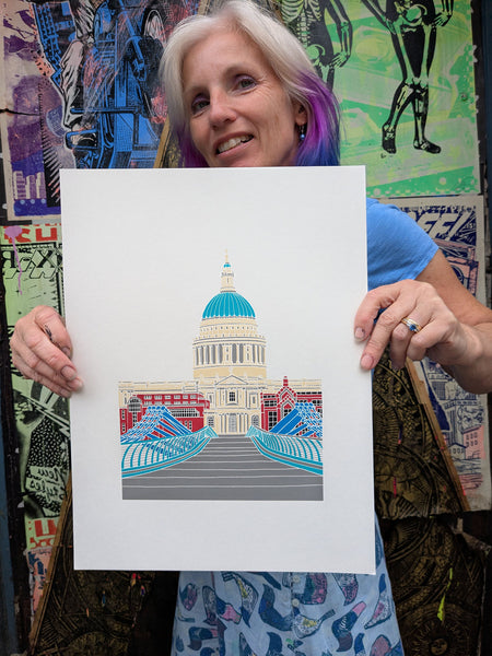 Liz holding a print of St. Paul's Cathedral with colourful architecture.