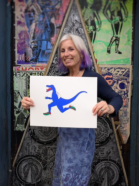 Liz holding a Print of a Blue dinosaur with red and green shoes 