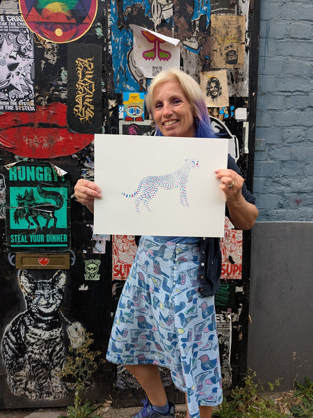 A stylised spotted cheetah  screen print on a white background held by Liz