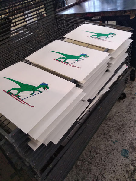 Print of a Green velociraptor on red skis with a blue bobble hat