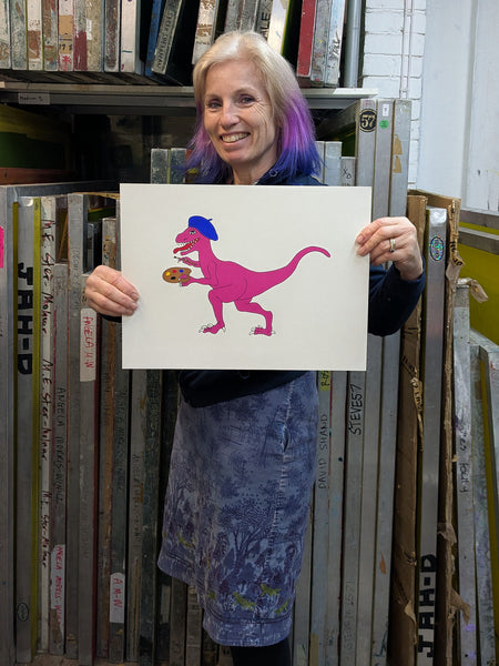 Print of a pink dinosaur in a blue beret holding a palette and paint brush held by Liz